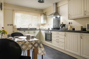 a kitchen with white cabinets and a table in it at Miners Cottage in Blaenau-Ffestiniog