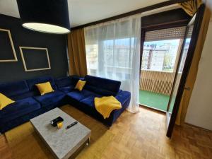 sala de estar con sofá azul y almohadas amarillas en Stan na dan Koprivnica-Comfort, en Koprivnica