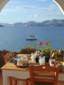 una mesa con comida y un barco en el agua en Aegean Villa-On beach apartment! Ideal choice! en Masouri