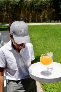 un homme dans un chapeau tenant une assiette avec une boisson dans l'établissement Elysian villa, à Spetses