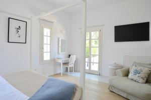 - une chambre blanche avec un lit et un canapé dans l'établissement Elysian villa, à Spetses
