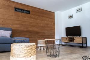 a living room with a blue couch and a tv at Gîte de la Ravanne in Ramonchamp