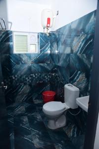 a blue tiled bathroom with a toilet and a sink at LILAC INN in Kodaikānāl