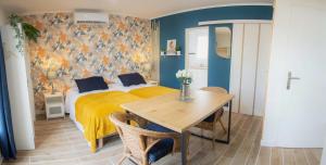 een slaapkamer met een bed en een tafel met een gele deken bij Le colibri in Cazaubon