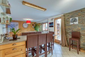 a kitchen with a bar with brown chairs at Le Repaire de l'Ours - 10min des pistes in Domancy