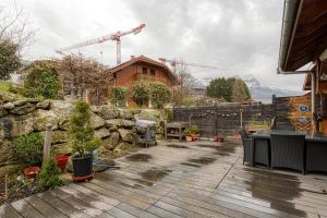 a patio with chairs and a stone wall and a building at Le Repaire de l'Ours - 10min des pistes in Domancy