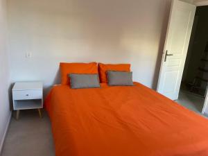 ein Schlafzimmer mit einem orangenen Bett mit zwei Kissen in der Unterkunft COLORS by Reine du Sud, proche des Grands Buffets in Narbonne