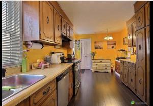 cocina con paredes amarillas y armarios de madera en Cozy House B&B, en Niagara Falls