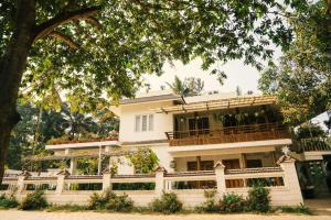 a large white house with a balcony at Mistygreen Homestay Thekkady in Thekkady