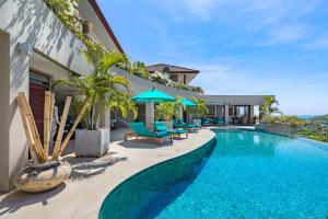 a pool with chairs and umbrellas next to a building at Panorama Summit - Private Pool with Sunset View in Plai Laem