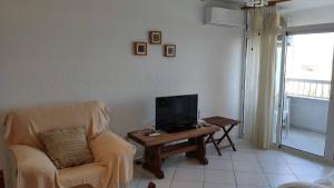 Sala de estar con silla y mesa con TV en Don Paco - Front Line Of The Beach Apartment en Roquetas de Mar