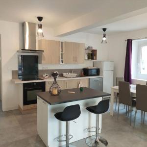 une cuisine avec un comptoir, des chaises et une table dans l'établissement Maison au calme climatisée avec véranda, à Lapeyrouse-Fossat