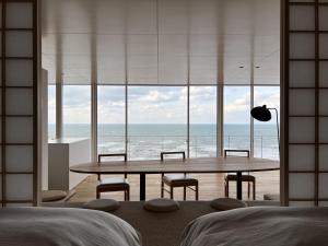 um quarto com uma mesa e cadeiras e o oceano em Cliff House Morai em Ishikari