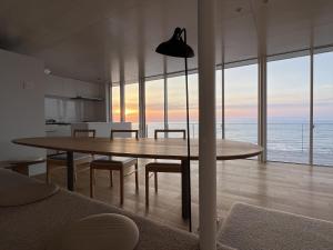 uma sala de jantar com uma mesa e vista para o oceano em Cliff House Morai em Ishikari