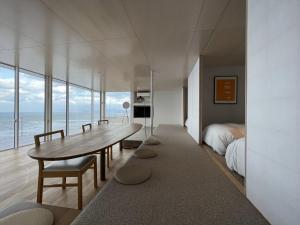 a bedroom with a table and a bed and the ocean at Cliff House Morai in Ishikari