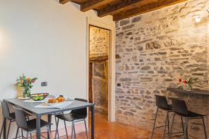 una mesa y sillas en una habitación con una pared de piedra en Antiche Mura Como by Rent All Como, en Como