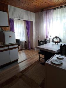 a living room with a table and a kitchen with windows at Smeštaj u Novoj Varoši, Zlatar in Nova Varoš