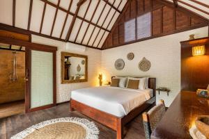 a bedroom with a large bed and a bathroom at Rimba Villas Gili Air in Gili Islands
