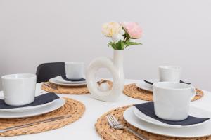 a table with plates and cups and a vase with flowers at City Centre & Cosy Apartment by Renters in Gdańsk