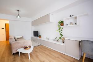 een witte woonkamer met een bank en een tafel bij City Center Accommodation - 404 in Reşiţa