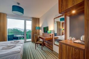 a hotel room with a bed and a desk and a mirror at Solina Resort in Polańczyk