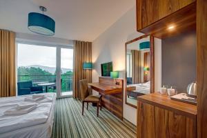 Pokój hotelowy z łóżkiem, biurkiem i lustrem w obiekcie Solina Resort w Polańczyku