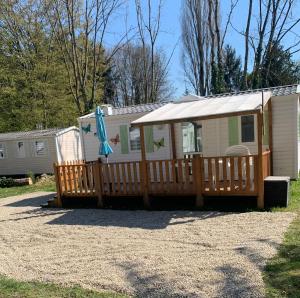 a mobile home with a deck and an umbrella at Mobil home climatisé Proche Europa Park in Boofzheim