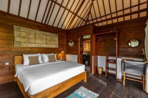 a bedroom with a bed and a chair in a room at Rimba Villas Gili Air in Gili Islands