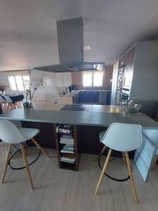 uma cozinha com um grande balcão e duas cadeiras brancas em Tossal Home em Castillo del Reboller