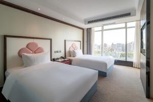 Postel nebo postele na pokoji v ubytování Suning Universal Hotel ALL-SUITES