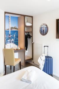 a bedroom with a bed and a desk and a boat at Hôtel Confort Le Moulin Rouge in Terrasson-Lavilledieu