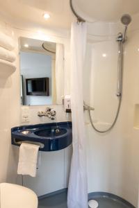 W łazience znajduje się umywalka i prysznic. w obiekcie Hôtel Confort Le Moulin Rouge w mieście Terrasson