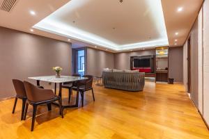 a living room with a table and chairs and a couch at Suning Universal Hotel ALL-SUITES in Nanjing