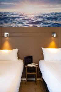 2 camas en una habitación con un cuadro en la pared en Hôtel Confort Le Moulin Rouge, en Terrasson-Lavilledieu