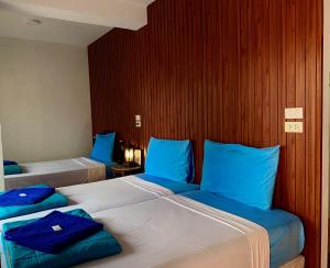two beds in a hotel room with blue pillows at Ban Wiang Guest House in Chiang Mai