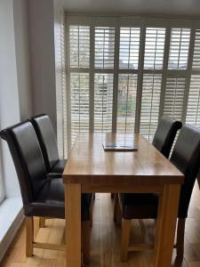 a wooden table with black chairs and a laptop on it at Bluebell Cottage - private coach house, garage & parking in Greenhithe