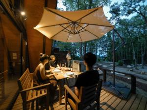 Villa Yoshino - Vacation STAY 01568v في أزومينو: مجموعة أشخاص يجلسون على طاولة تحت مظلة