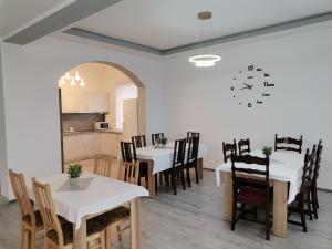 a dining room with tables and chairs and a clock on the wall at Vila President Sovata in Sovata