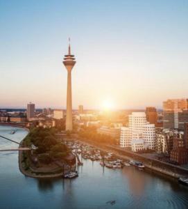 vistas a una ciudad con una torre y un río en MAX Hotel Düsseldorf Self-Check-in, en Düsseldorf