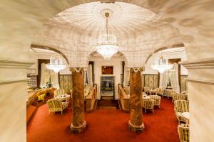 uma grande sala com mesas e cadeiras e um lustre em Grand Hotel Bellevue - adults only em Merano