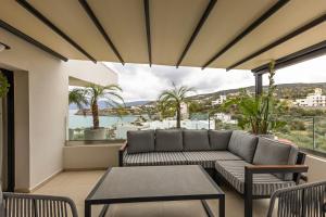ein Wohnzimmer mit einem Sofa und einem Tisch auf dem Balkon in der Unterkunft Lazar Lux Suites - Ammoudara in Agios Nikolaos