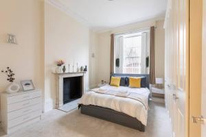 a bedroom with a bed with yellow pillows and a fireplace at Cozy Flat in the Heart of London in London