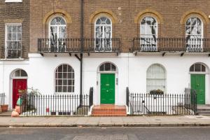 a building with green and red doors on a street at Cozy Flat in the Heart of London in London