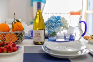 Casa Vacanze San Michele في ألغيرو: طاولة مع زجاجة من النبيذ وصحن من الفاكهة