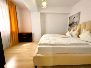 Schlafzimmer mit einem weißen Bett mit Kopfteil in der Unterkunft City Center Accommodation - 310 in Reşiţa