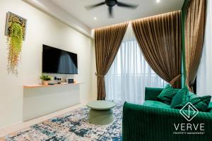 a living room with a green couch and a tv at Ipoh Cove Premium Suites by Verve in Ipoh