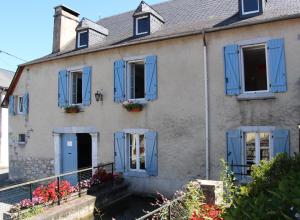 uma casa com persianas azuis e flores nas janelas em GITE DU MOULIN em Arudy