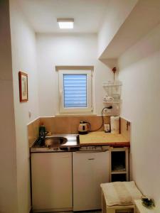 una pequeña cocina con fregadero y ventana en Rooms Garden - with a view, en Dubrovnik