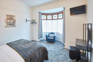 a bedroom with a bed and a chair and a window at Apartment 1 - Khyber Lodge Apartments in Whitby
