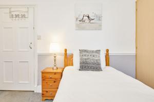 ein Schlafzimmer mit einem Bett mit weißer Bettwäsche und einer Lampe in der Unterkunft Apartment 1 - Khyber Lodge Apartments in Whitby